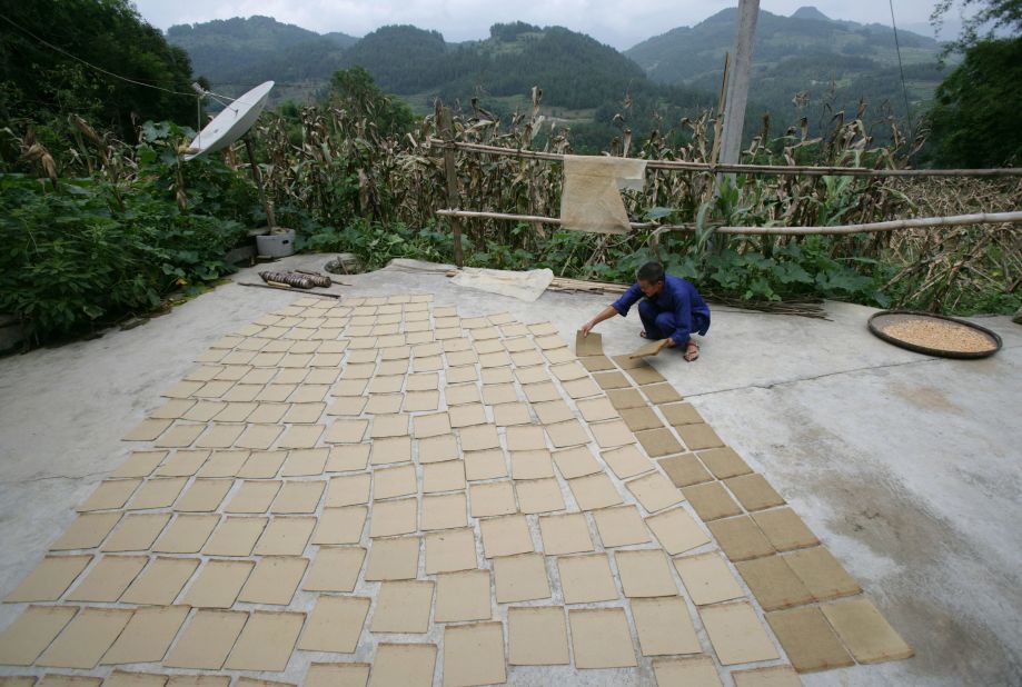 A worker arranges sheets of handmade bamboo paper on the ground to dry at a papermaking workshop in the village of Tianwan in China. The paper is mainly used for packaging of local farm products. 