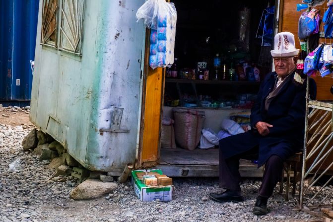 A Pamiri man wearing a traditional hat sits outside his market stall in Murghab, Tajikistan.