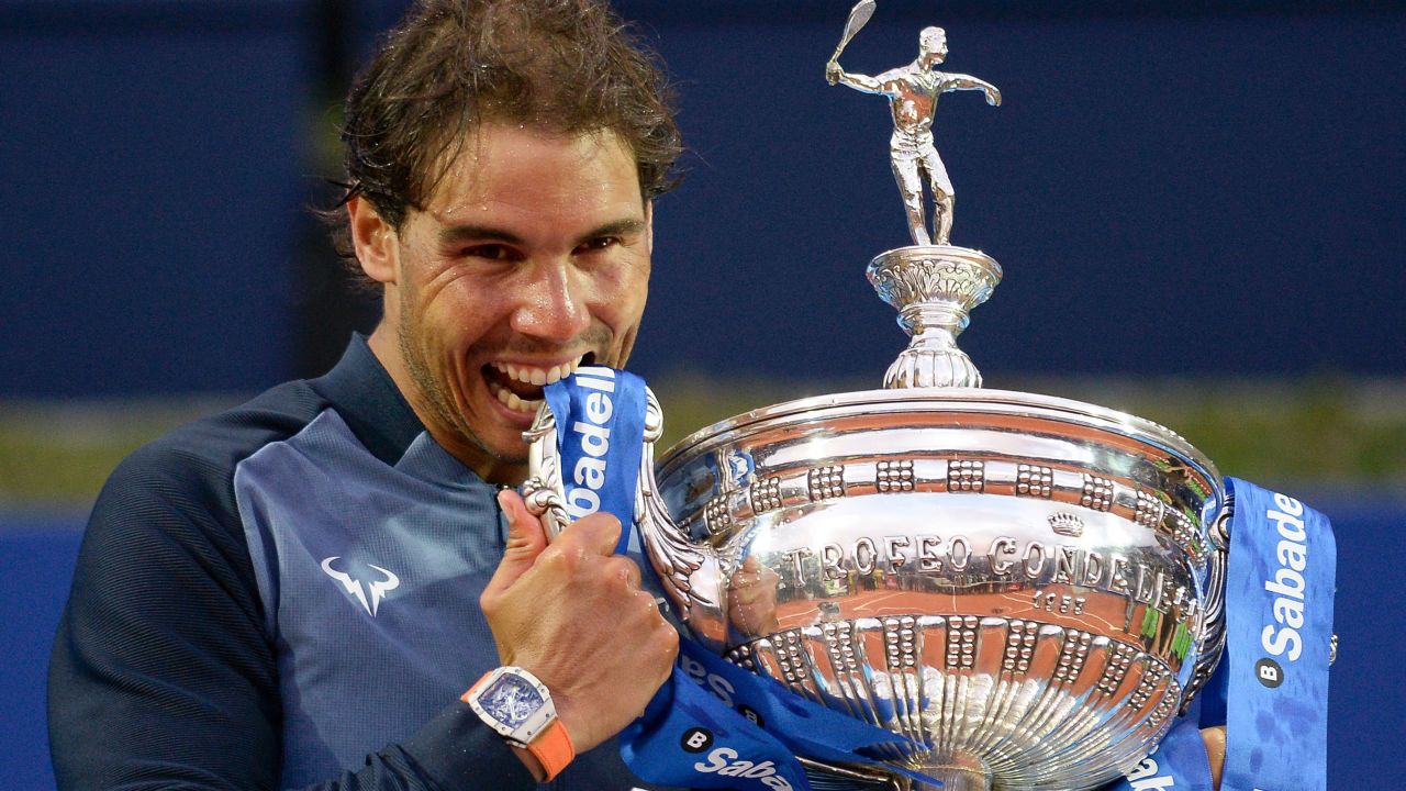 Rafael Nadal takes his customary bite out of the Barcelona Open trophy after regaining it from Japan's Kei Nishikori.
