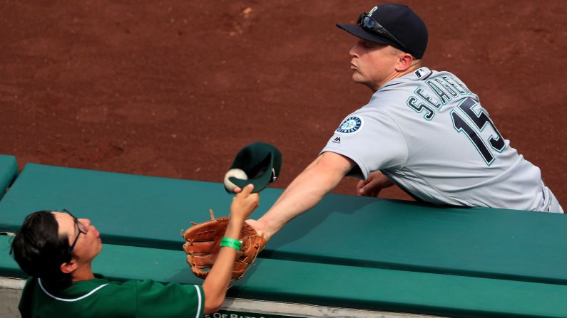 A fan in Anaheim, California, tries to catch a foul ball with his hat as Seattle's Kyle Seager reaches with his glove on Sunday, April 24. 
