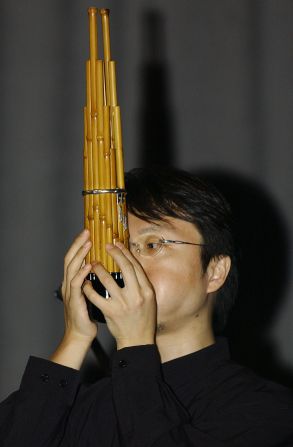 A Japanese musician plays a traditional Japanese musical instrument called "Sho", which is made up of 17 slender bamboo pipes with reeds gathered together in one bundle. It makes a sound similar to an organ. 