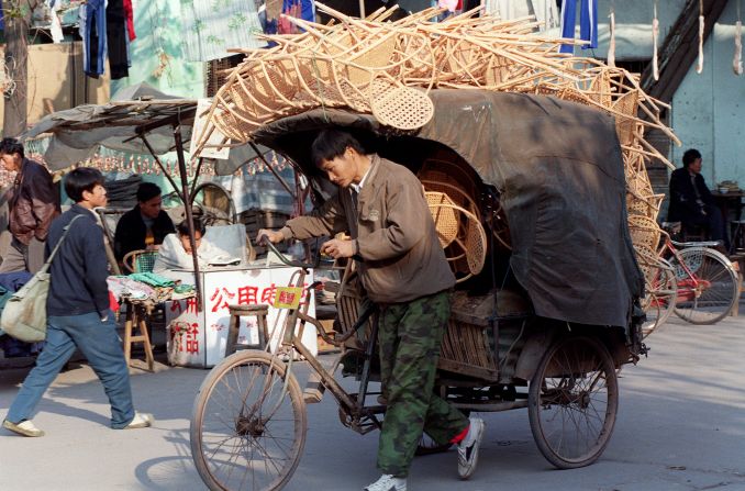A man cycles a cart loaded with chairs made from bamboo for market in Guangzhou City, China. Bamboo is popular for furniture, and it's grown in the outskirts of the city.        