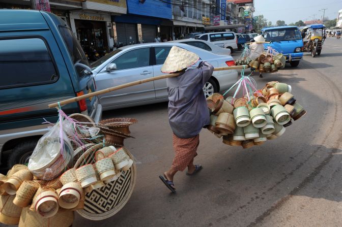 A woman in Laos carrying handmade bamboo baskets, a typical sight across many parts of Asia. 