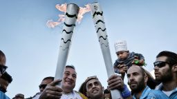 In a show of solidarity, president of the Hellenic Olympic Committee, Spyros Kapralos (L),  passed the Olympic Flame to a Syrian refugee, Ibrahim al-Hussein at the Eleonas refugee camp in Athens Tuesday.