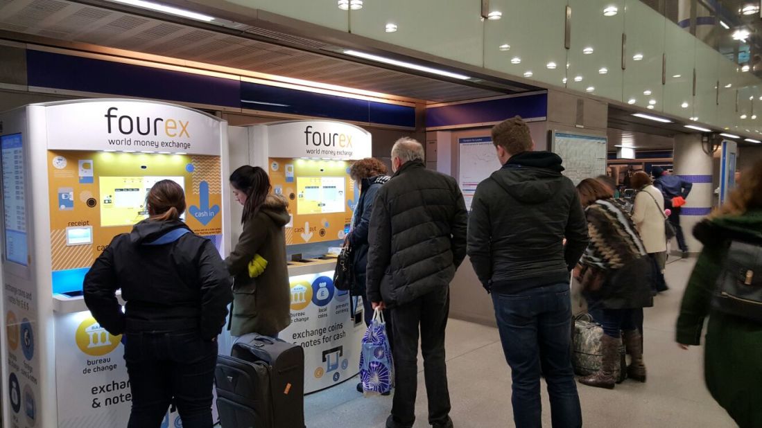Customers queue up to use Fourex's currency machines in London's King's Cross station. 