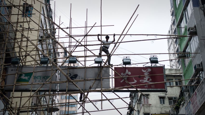 A worker balances on a bamboo scaffolding above the streets in Hong Kong on March 20, 2014. Hong Kong's bamboo scaffoldings remain a common sight high above the streets of the city, scaling the sides of towering, ultra-modern steel and glass buildings on traditional bamboo poles linked through ancient design concepts.     AFP PHOTO / Philippe Lopez        (Photo credit should read PHILIPPE LOPEZ/AFP/Getty Images)