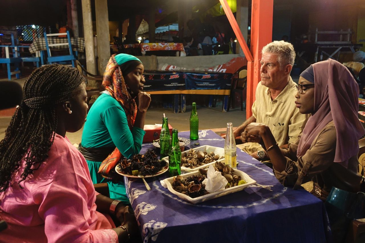 Bourdain shares clams and sea urchins with Oumy N'Dour, Fama Diouf (far left) and Minielle Tall (far right) at Vitres de Sokone in Dakar.