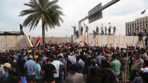 Supporters of Shiite cleric Muqtada al-Sadr walk over the blast walls surrounding Baghdad's highly fortified Green Zone Saturday, April 30, 2016. 