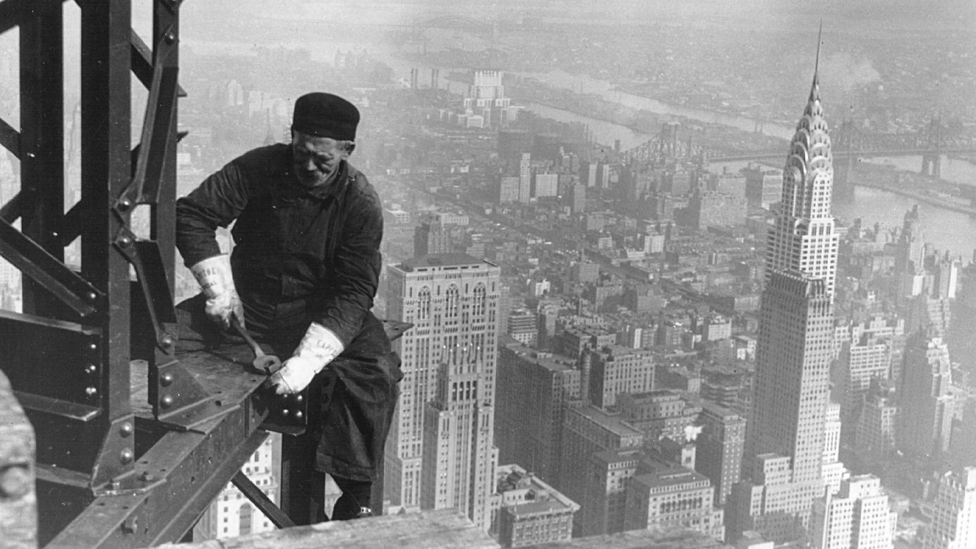A worker sits on a beam during the construction of the Empire State Building. Construction began on March 17, 1930, with 3,000 workers building 4.5 floors per week.