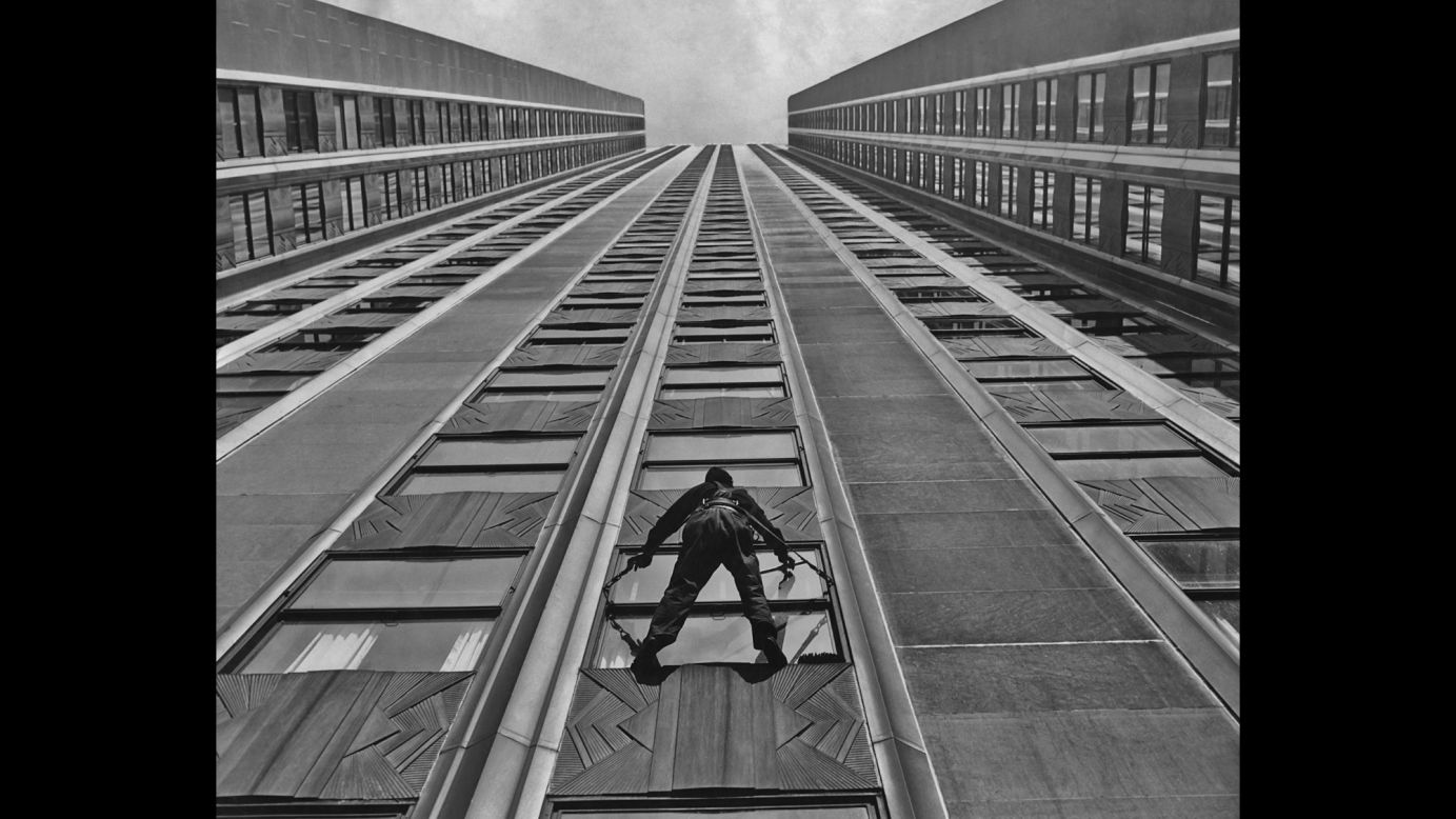 A window cleaner hangs suspended from the exterior of The Empire State Building while using a leather safety harness in 1935.