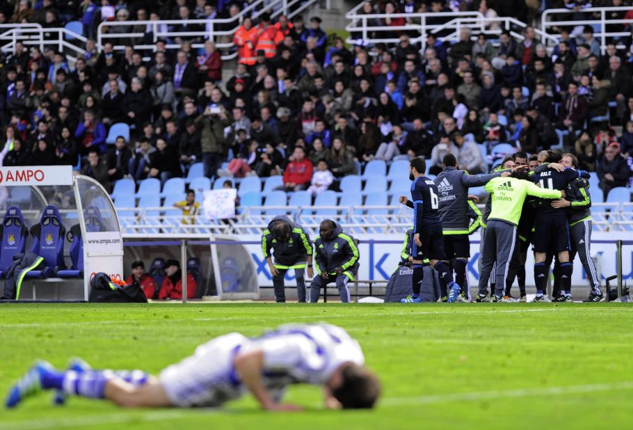 Real Madrid's players celebrate Bale's goal in the background while a Real Sociedad player feels the anguish face down. 