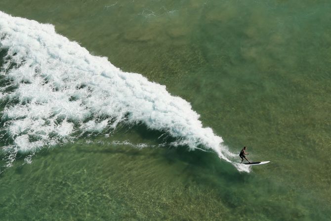 A stand-up boarder rides a wave at Manly Beach, one of Sydney's most popular beaches.