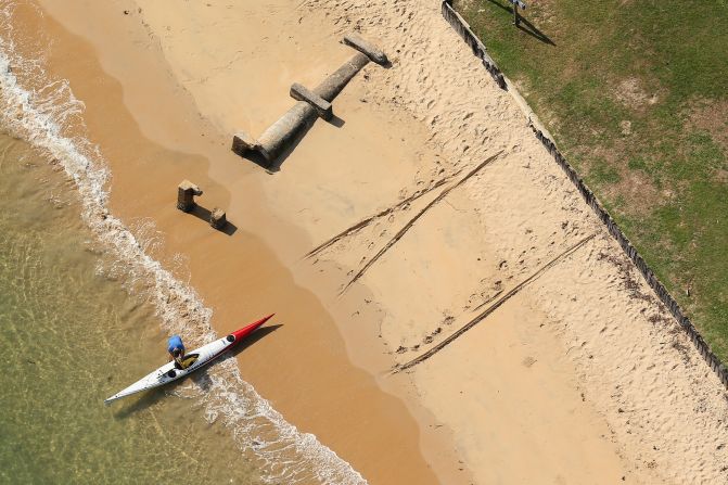 A kayaker prepares to launch his craft from the beautiful sands by the side of Pittwater.