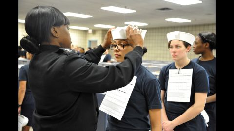 Engineman 2nd Class Shanice Floyd, a recruit division commander, ensures the proper fit of Megan Marte's hat during uniform issue Monday, April 4, in Great Lakes, Illinois. Marte was among the first female recruits to be issued the "Dixie cup" hat as part of the Navy's efforts at gender equality.