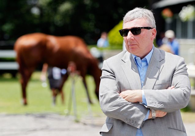 Nyquist's owner J. Paul Reddam speaks in the foreground as Kentucky Derby winner I'll Have Another grazes behind him outside of barn two on June 8, 2012 in Elmont, New York.