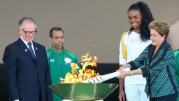 BRASILIA, BRAZIL - MAY 03:  Dilma Rousseff, President of Brazil, lights the Olympic torch with Brazilian Olympic Committee Carlos Nuzman (L) and first torch bearer, volleyball player Fabiana Claudino at the Palacio do Planalto on May 3, 2016 in Brasilia, Brazil. The Olympic torch will pass through 329 cities from all states from the north to the south of Brazil, until arriving in Rio de Janeiro on August 5, to lit the cauldron.  (Photo by Buda Mendes/Getty Images)