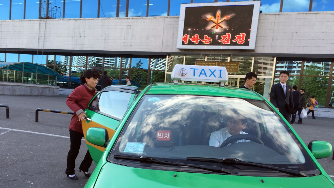 A woman gets into a taxi outside a new Pyongyang department store. The North Korean capital now has several taxi companies.