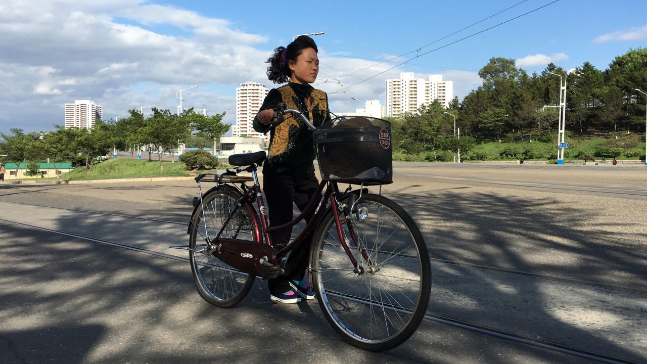 A woman walks her bike along Kwangbok "Liberation" street in Pyongyang on May 4 after a day of work and rehearsals for the upcoming congress.