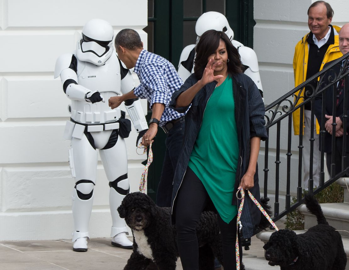 President Obama bumps fists with a Star Wars Stormtrooper as First Lady Michelle Obama waves to the crowd at the annual Easter Egg Roll at the White House in Washington, DC, on March 28, 2016.