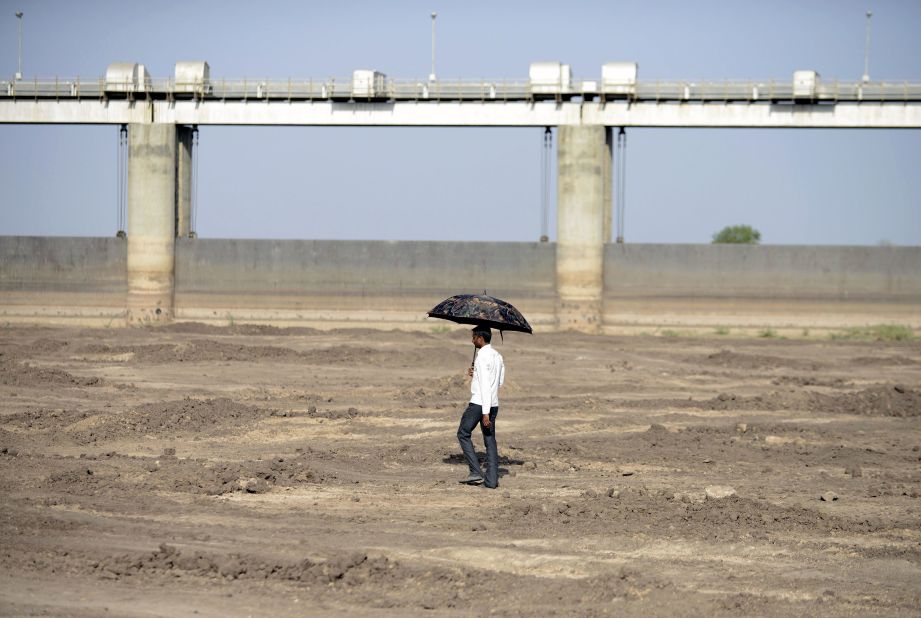A man walks on the dry reservoir bed next to Gunda Dam in India's western Gujarat state on Friday, April 1.