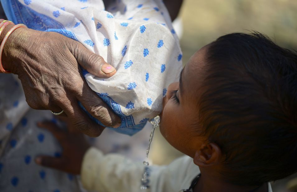 A woman tries to filter water with her sari as a child drinks in the Shankargarh area on April 21.