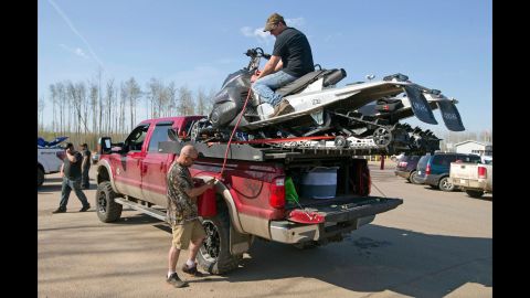 Robert Parker, left, and Matt Jones siphon gas from two snowmobiles for their truck on May 4.