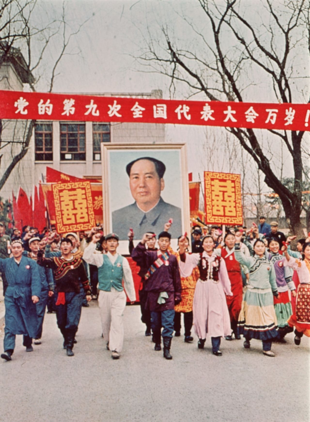 Supporters march down the street carrying a large poster of Chairman Mao Zedong.