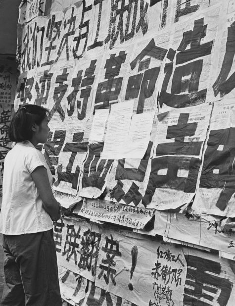 A girl reads big character posters (dazebao) covering the windows of a department store in Guangzhou. Such posters were used for spreading propaganda and attacking "class enemies."