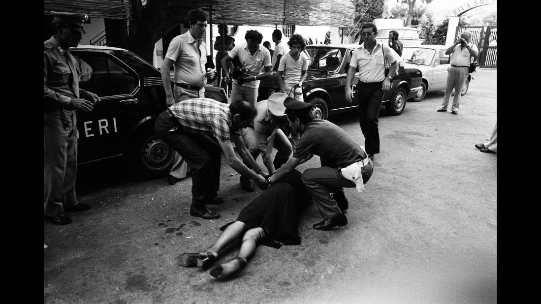 A woman falls to the ground after hit men killed a hotel owner in Capaci, Italy, in 1980.