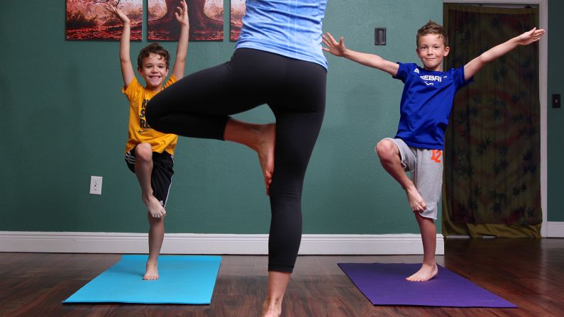 Santas, Luke and Nolan stand in happy hopping tree pose, which improves balance, coordination and movement control.