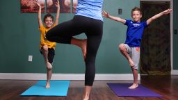 Dana Santas, her son and one of his friends stand in Tree Pose. 