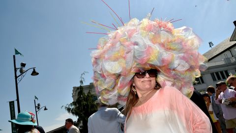 A festive fan poses in a hat resembling an explosion of pastel ruffles. 