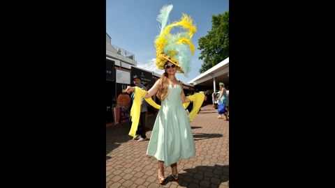 A fan shows off her feather-and flower adorned hat. 