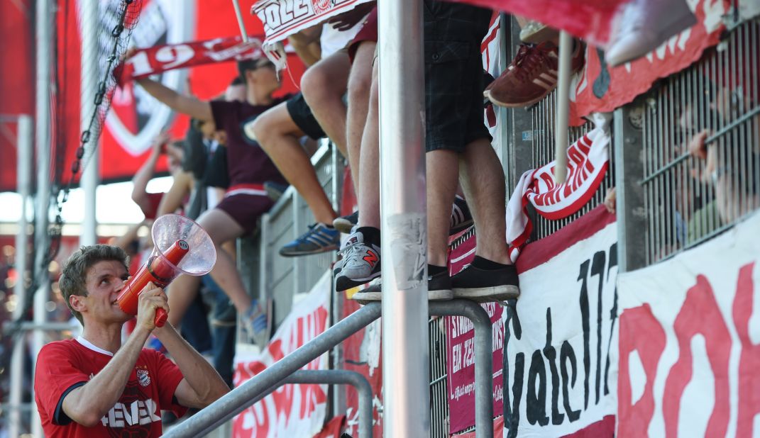 Bayern Munich striker Thomas Mueller leads supporters in chants after the match.