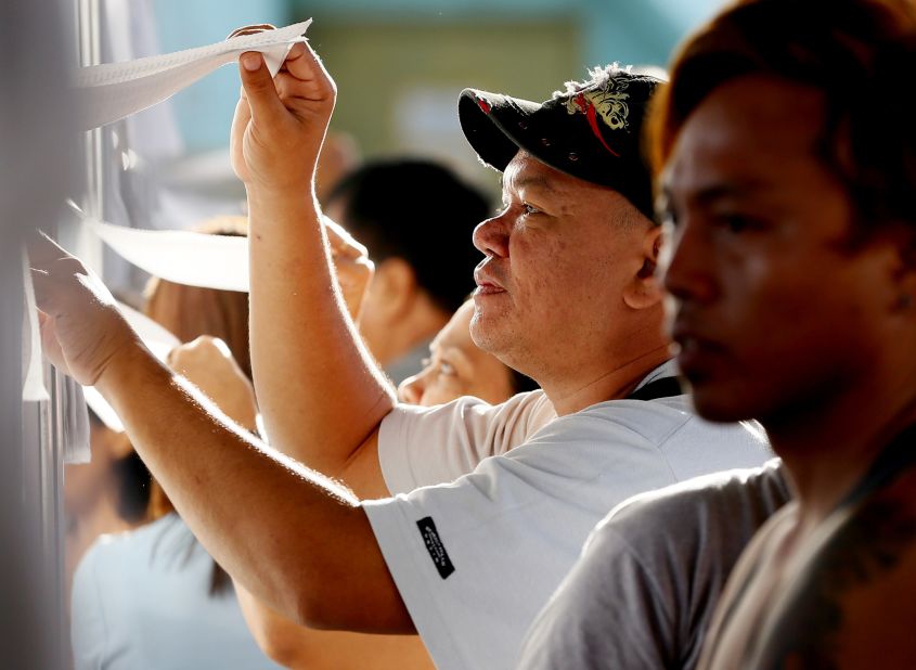 Filipino voters check the voters' list as they queue up to cast their choice for the presidential elections in Davao City in southern Philippines on May 9, 2016. 