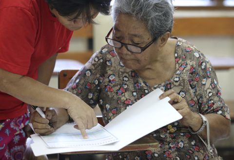 Eighty-year-old Dioleta Esteban is assisted as she votes at a polling center in suburban San Juan, east of Manila, Philippines on Monday, May 9, 2016. 