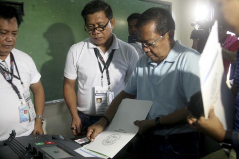 Presidential candidate and current Philippine Vice President Jejomar Binay (right) inserts his ballot into the vote counting machine inside a polling center at the San Antonio National High School in Makati, Philippines on May 9, 2016. 