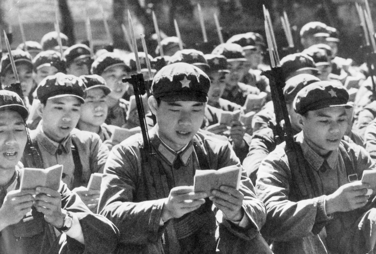 Chinese men in military uniforms reading from Mao's "Little Red Book" before starting their day. 