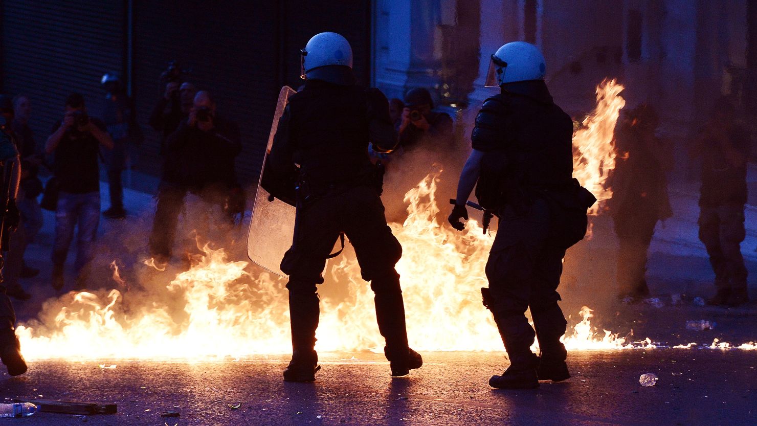 Police stand guard as protesters throw molotov cocktails at an anti-austerity protest in Athens, May 8, 2016.  