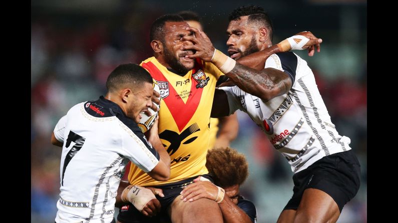 Edward Goma, a rugby player from Papua New Guinea, is tackled by Fiji players during a match in Sydney on Saturday, May 7.
