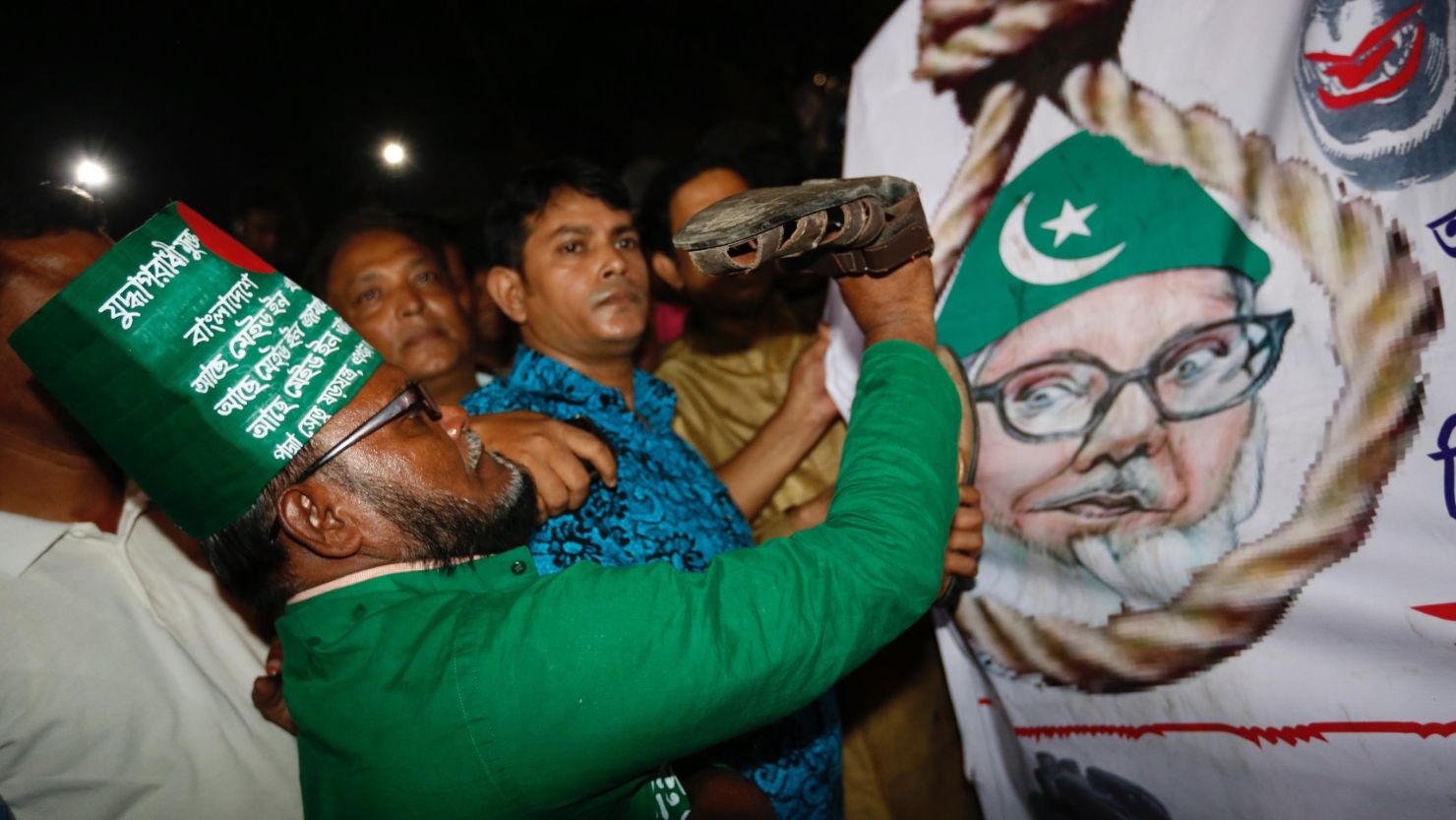 A Bangladeshi man throws a shoe at a poster of Motiur Rahman Nizami following the Jamaat-e-Islami party leader's execution.
