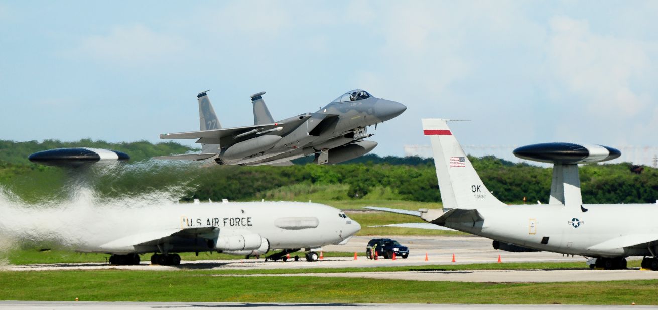 An F-15 Eagle takes off from the Andersen Air Force Base, Guam, flight line as two E-3 Sentries are seen in the background.