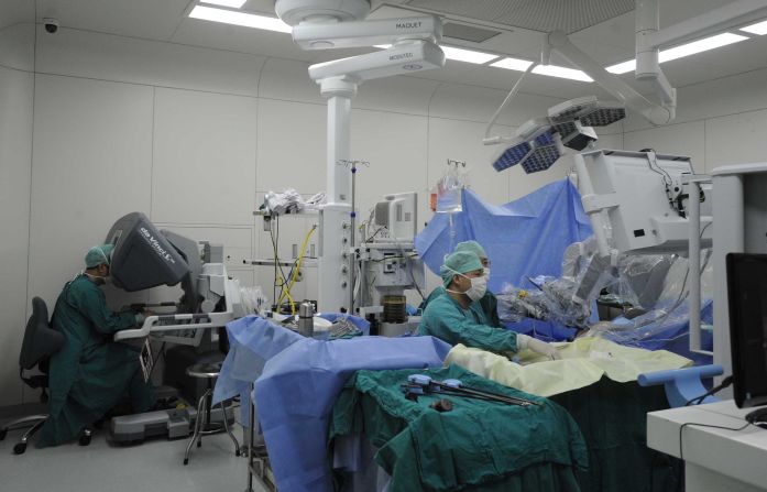 Here the surgeon (left) controls the da Vinci robot  to remove a tumor in a patient. The robot has a magnified 3D vision system which can give the surgeon a clearer view of the operation. 