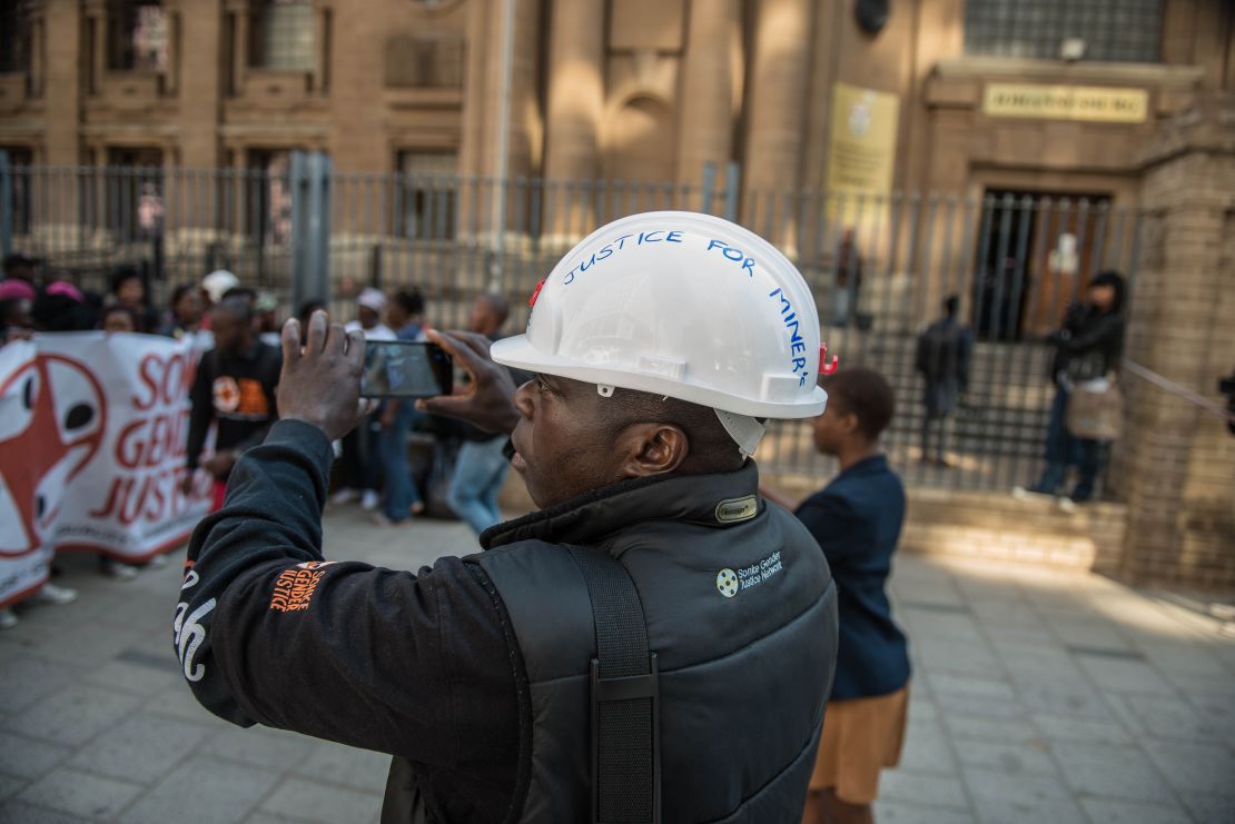A supporter of miners films a protest outside court in Johannesburg.