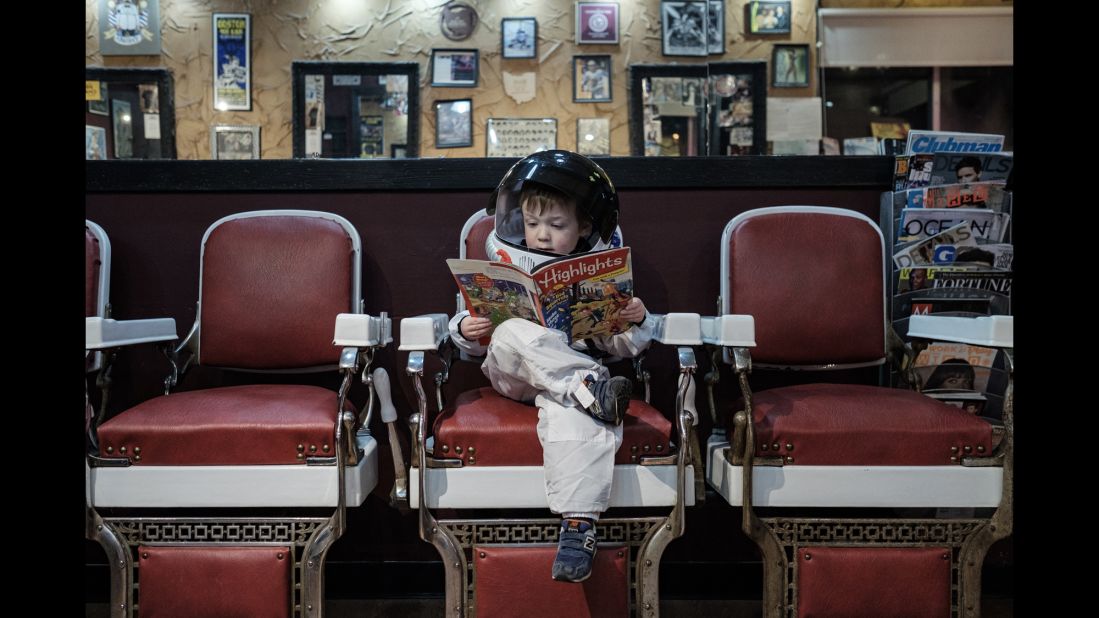 Aaron Sheldon's son, Harrison, reads a magazine inside a Columbus, Ohio, barbershop. He is wearing an astronaut costume for Sheldon's project "Small Steps Are Giant Leaps," which illustrates how children -- like astronauts -- are constantly exploring the world around them.