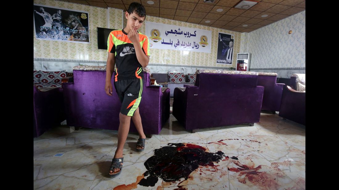 A boy walks past bloodstains and debris at a cafe in Balad, Iraq, that was attacked by ISIS gunmen on May 13, 2016. Twenty people were killed.