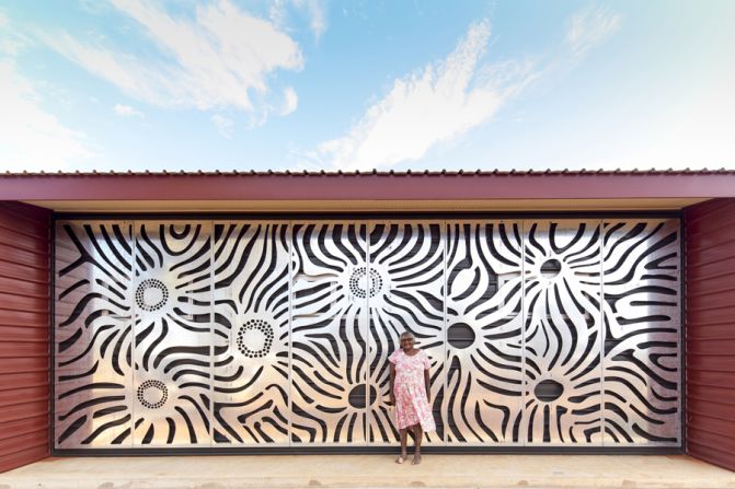 One of the community artists stands in front of the screen she designed. Aesthetically beautiful, the screens shade the building from the north, protecting it from the region's intense desert heat. 