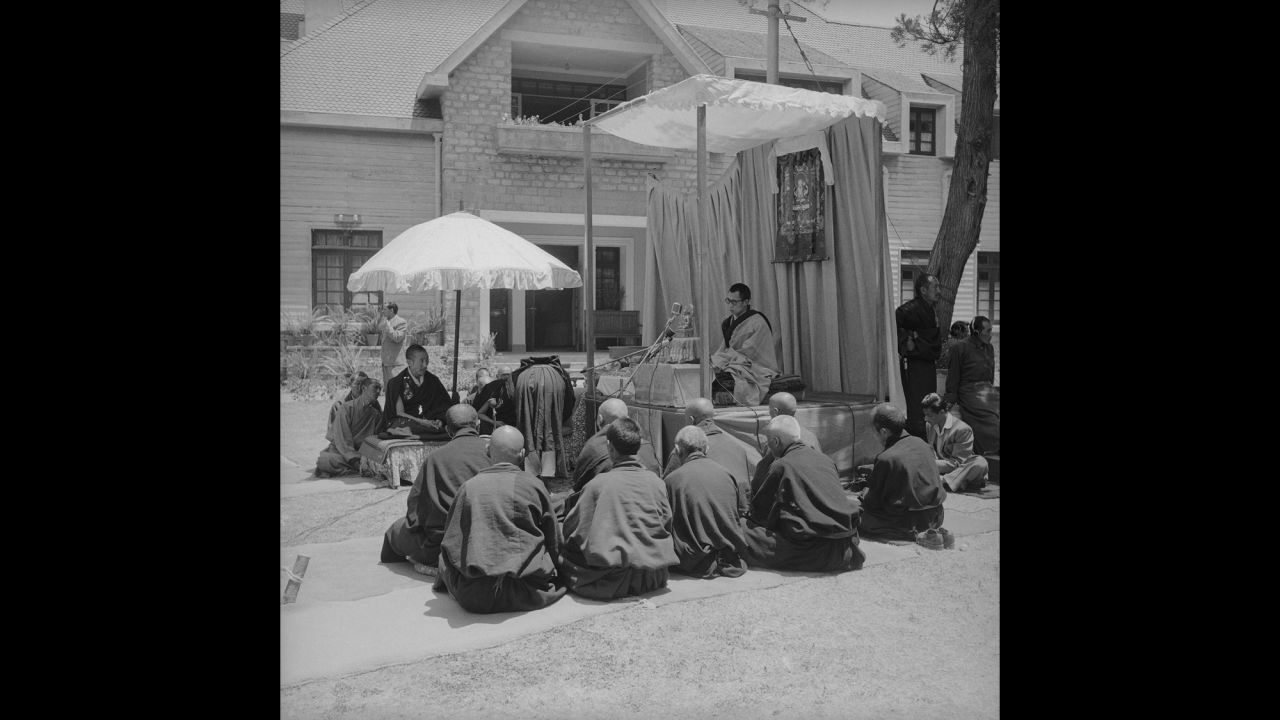 The Dalai Lama sits under a portrait of Buddha as he gives an address at the Birla House. Leading Tibetan monks sit on his left. His tutors sit on his right. During his address, the Dalai Lama expressed hope that the strife in his country was only a passing phase, and he urged the gathering to pray for a return of peace to Tibet.