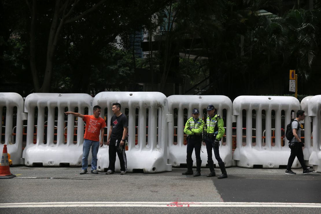 Police officers stand in front of large barricades erected along a road in Hong Kong on May 16, 2016.