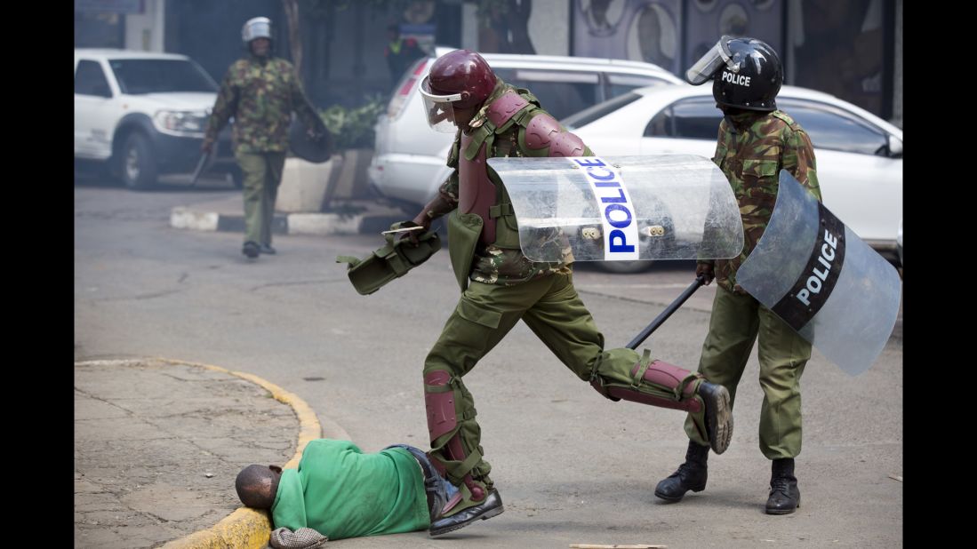 A Kenyan riot policeman repeatedly kicks a protester as he lies in the street after tripping  while trying to flee from them on Monday, May 16. Ben Curtis, Associated Press' East Africa photographer and acting bureau chief in Nairobi said this man was "chased across the street and fell down. As he lay motionless on the ground the riot policeman who had pursued him beat him with a stick, breaking it in half, and then continued to kick him half a dozen times, while two other police joined in. Eventually another officer walked up and directed the police to move away, leaving the man lying in the street. ... Later in the afternoon he was located in the Kibera slum of Nairobi -- injured but alive."